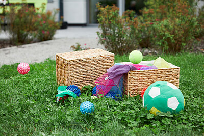 Geflochtene, eckige Körbe auf einer Wiese, drumherum einige Bälle und bunte Seile